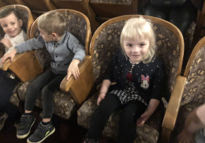 Dzieci siedzą w fotelach w teatrze.
